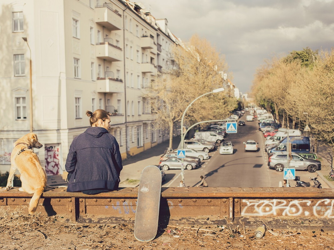 Mann sitzt mit Hund auf einer Brücke