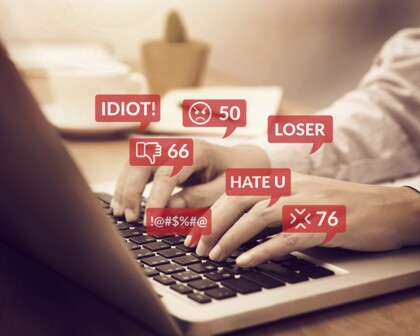 Hände auf Tastatur mit hassgefüllten Sprechblasen Hate Speech