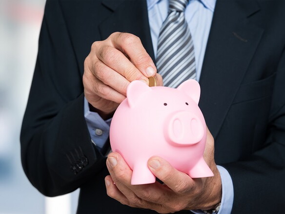 Mann wirft Münze in Sparschwein