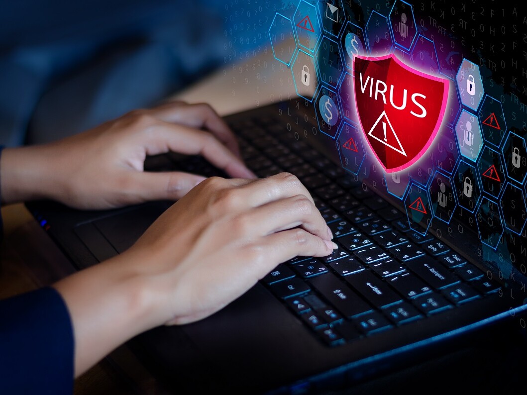 Hände auf Tastatur mit Virus auf Bildschirm
