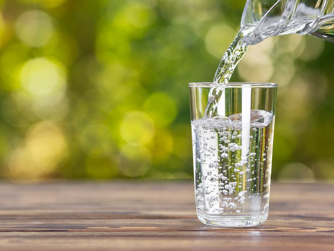 Kanne gießt Wasser in ein Glas