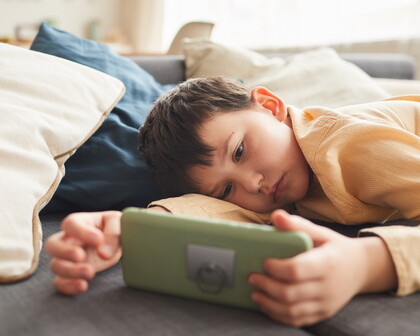 Kind nutzt ein Smartphone. Der EU KIDS Act soll Minderjährige bei Social Media, digitalen Diensten und KI-Systemen besser schützen.