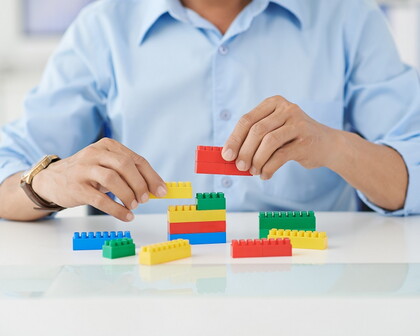 Mann spielt mit bunten Bausteinen