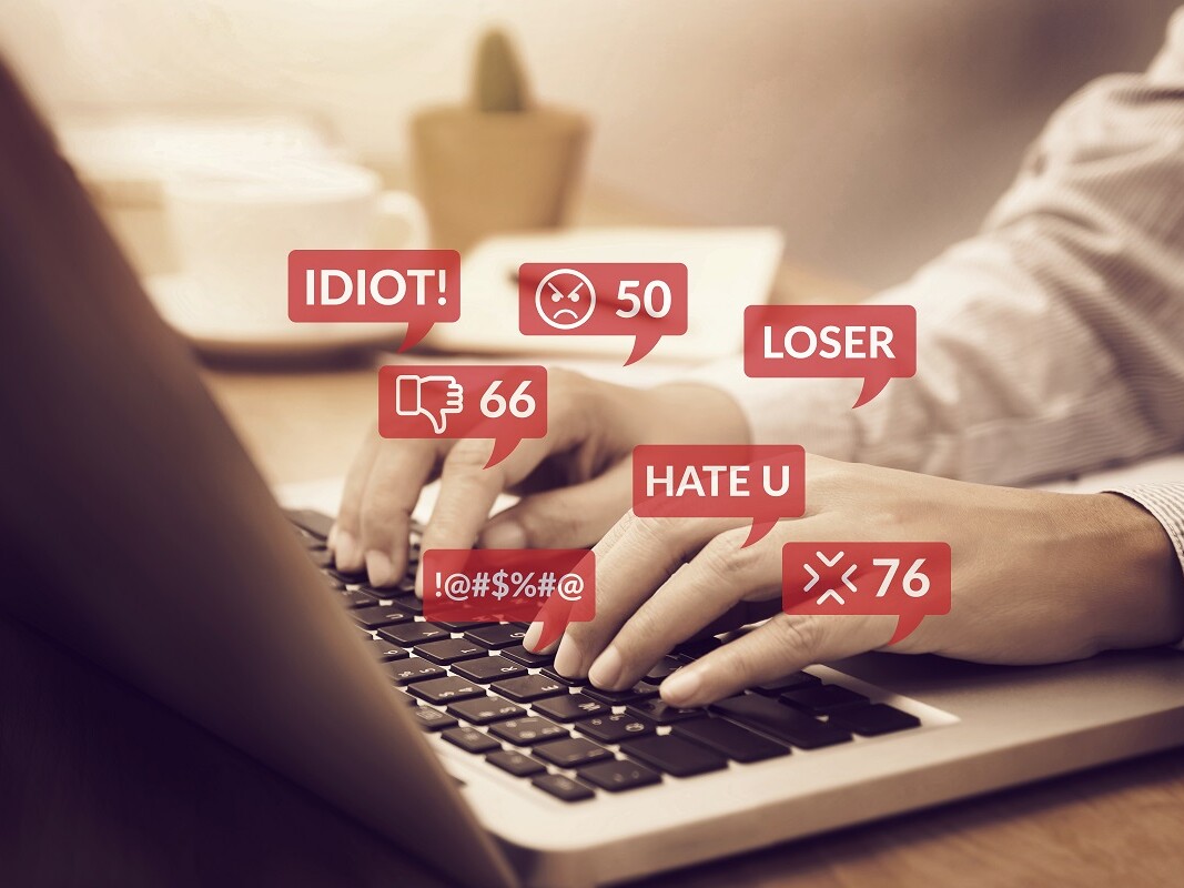 Hände auf Tastatur mit hassgefüllten Sprechblasen Hate Speech