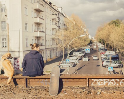 Mann sitzt mit Hund auf einer Brücke