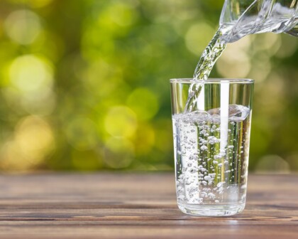 Kanne gießt Wasser in ein Glas