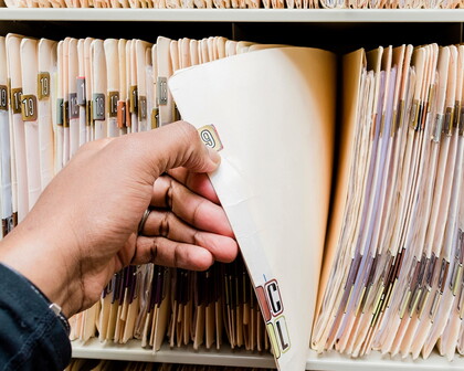 Hand nimmt Akte aus Regal