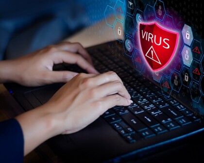 Hände auf Tastatur mit Virus auf Bildschirm