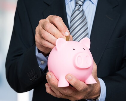 Mann wirft Münze in Sparschwein