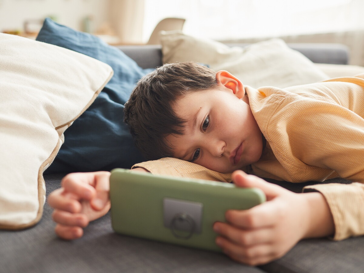 Kind nutzt ein Smartphone. Der EU KIDS Act soll Minderjährige bei Social Media, digitalen Diensten und KI-Systemen besser schützen.