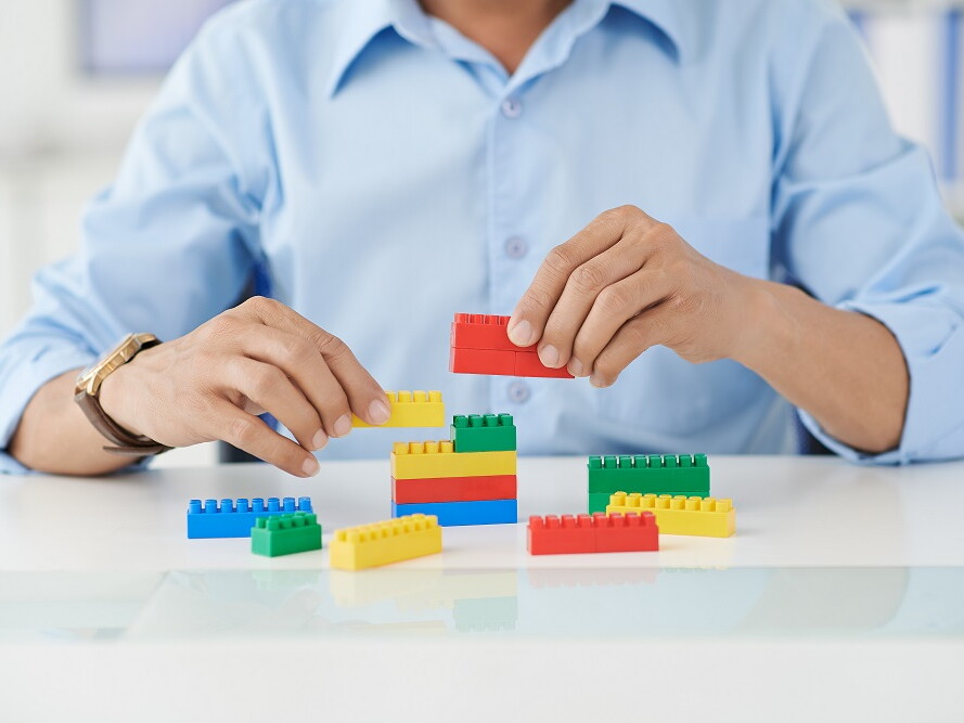 Mann spielt mit bunten Bausteinen